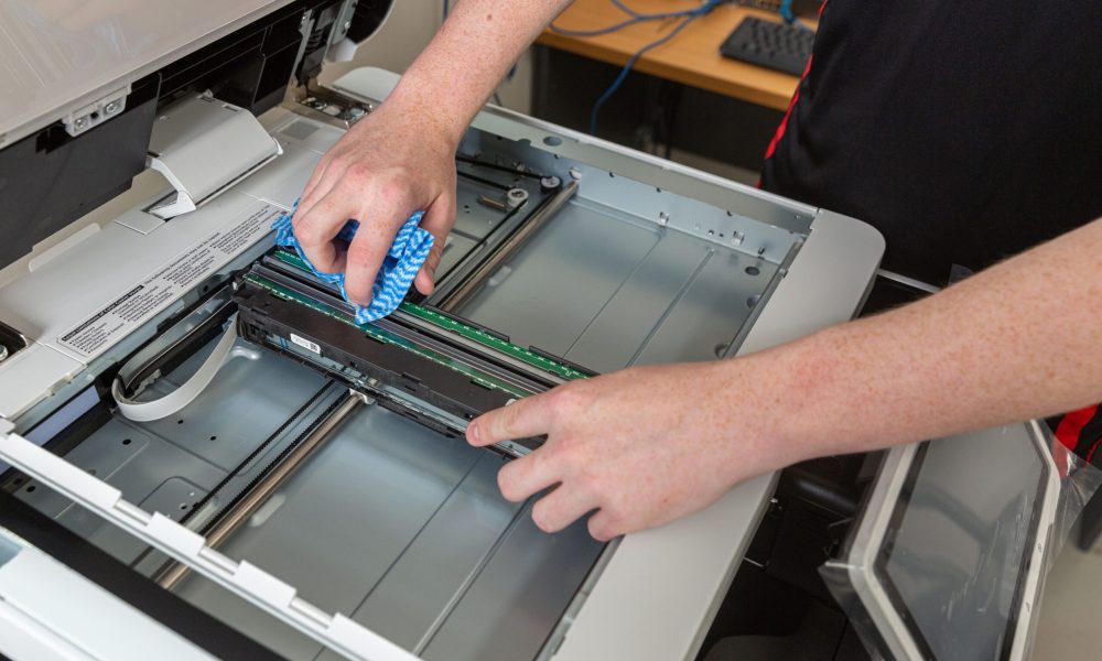 Someone cleaning photocopier scanner